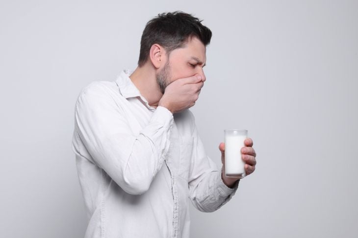 Man with glass of milk suffering from lactose intolerance