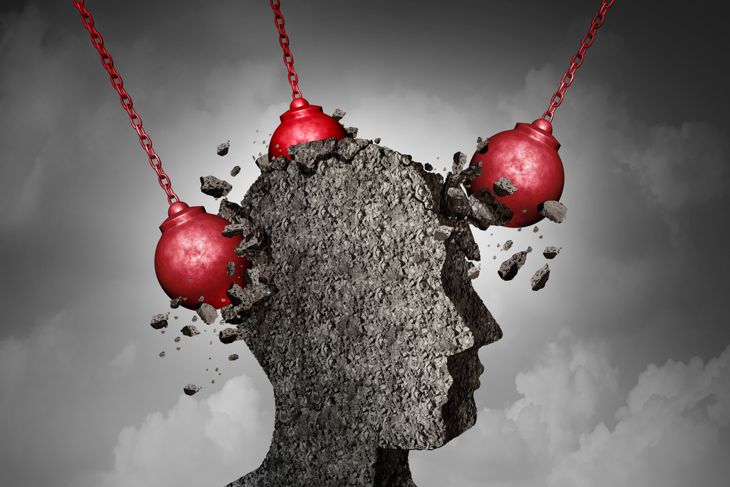 Painful Headache pain and pounding migraine concept as a human head made of cement being destroyed or renovated by a group of wrecking balls as a symbol for personal change