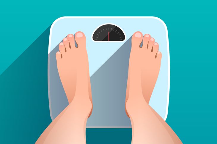 standing on bathroom scales over colored background, top view of feet