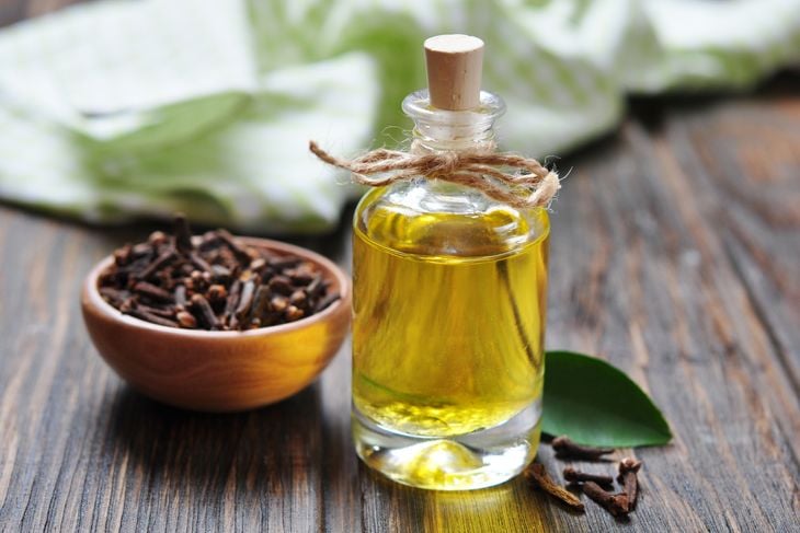 Oil of cloves in a glass bottle over wooden background