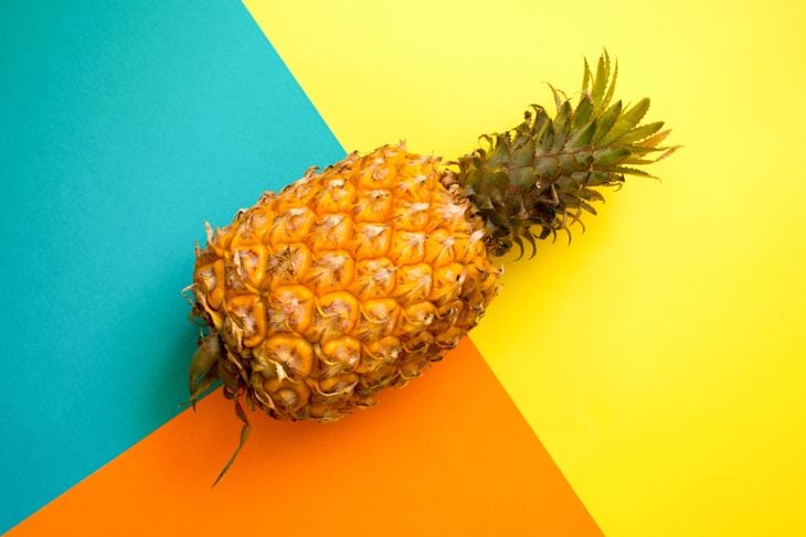 Ripe pineapple on a geometric pattern yellow, ornage and cyan colour background