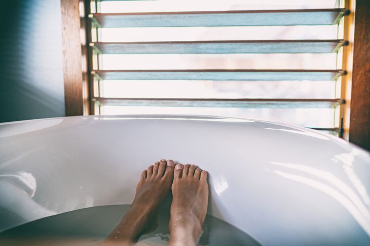 Bath soaking feet woman relaxing in hot bathtub water relaxation wellness foot therapy.