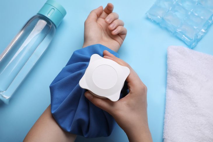 Woman with cold compress on light blue backgr