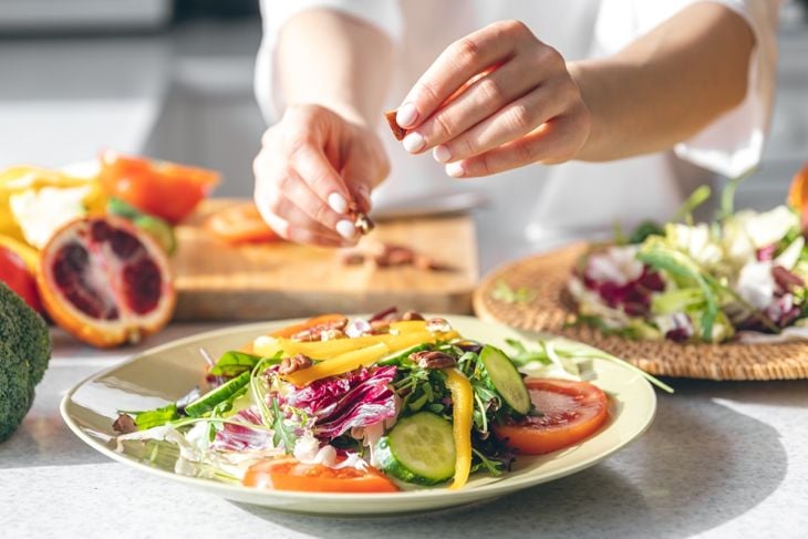A woman making fresh vegetable salad, close-up, concept of diet and healthy eating.