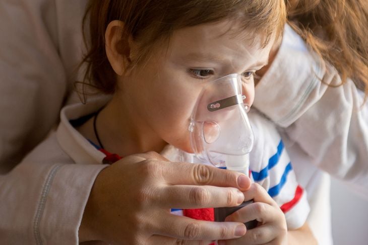 Young woman with son doing inhalation with a nebulizer at home