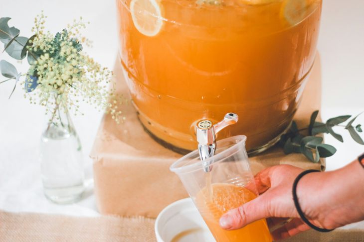 Person pouring kombucha into a clear plastic cup photo