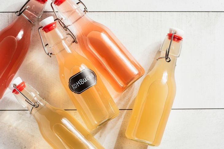 A couple of kombucha bottles of liquid sitting on top of a table photo