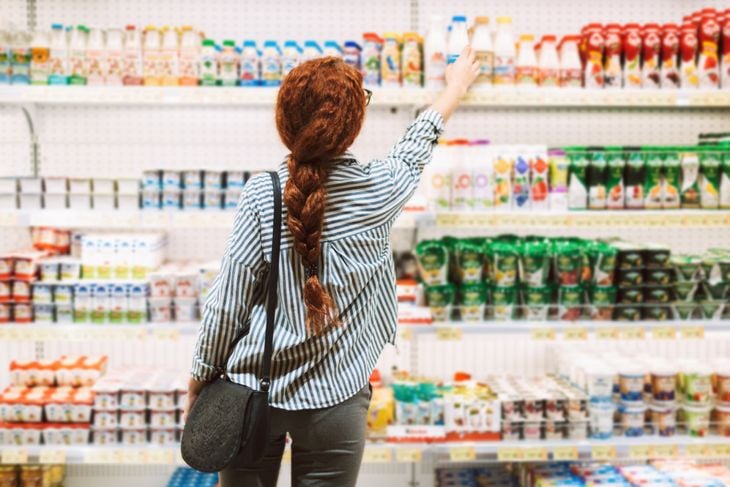 Woman in a striped shirt choosing dairy products in modern supermarket