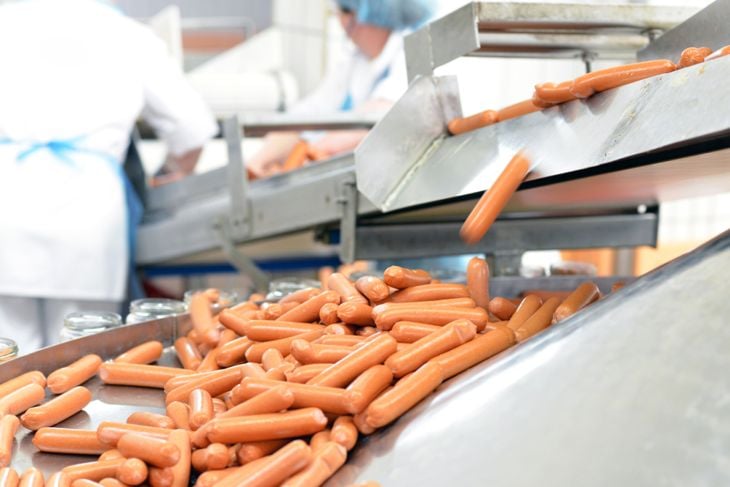 food industry: workers in the production of original German bratwurst in a large butcher's shop