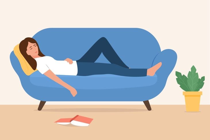 Young woman sleeping on sofa with fallen book