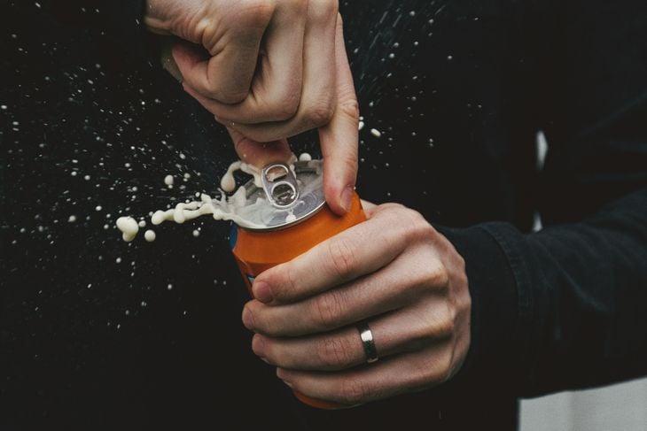 A photograph of a person opening a soda in their hand