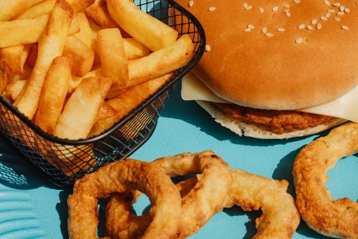 A hamburger and some onion rings on a blue plate photo