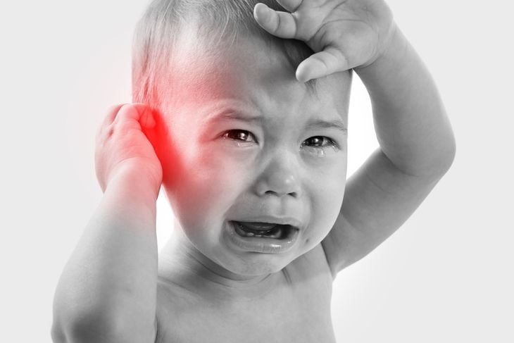Closeup of little crying baby suffering from a ear pain