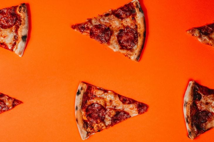 Pepperoni pizza slices on an orange background