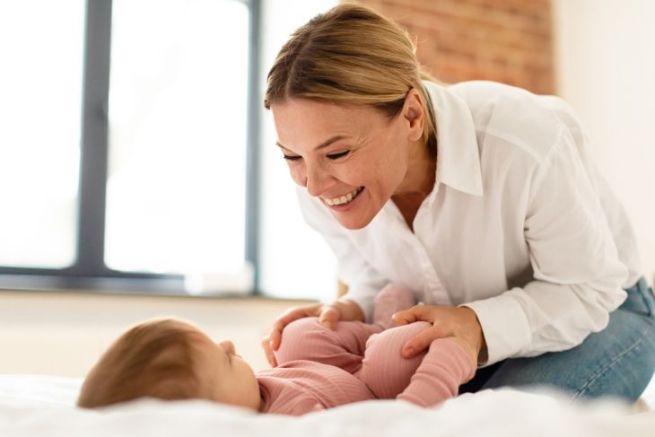 Happy mother bonding with infant while spending time together in bedroom