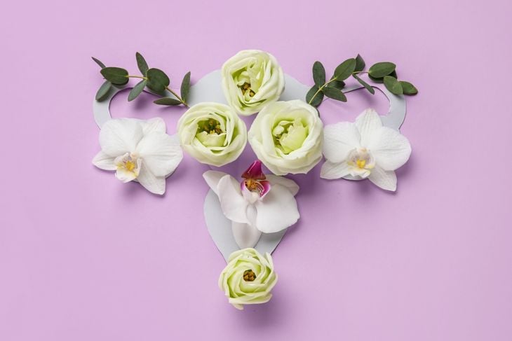 Uterus made of beautiful flowers on purple background