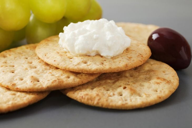 Cottage cheese with crackers, grapes and olives on a dark platter.