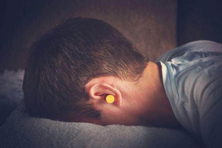 yellow ear plugs in the ears of a man