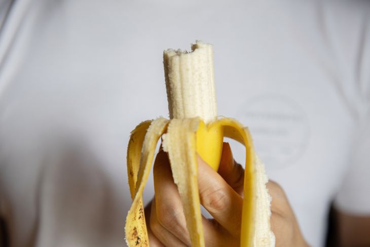 A man holding bited banana