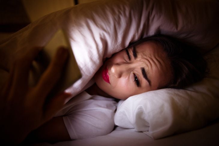 Close-up photo of a tired girl, lying in her bed under the blanket
