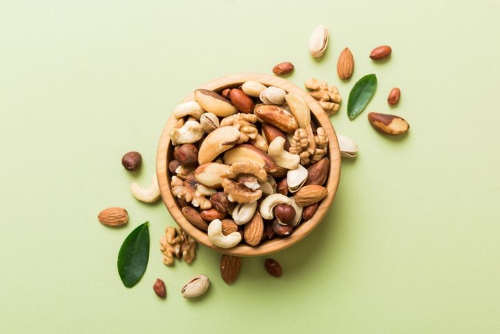 mixed nuts in bowl. Mix of various nuts on colored background. pistachios, cashews, walnuts, hazelnuts, peanuts and brazil nuts.