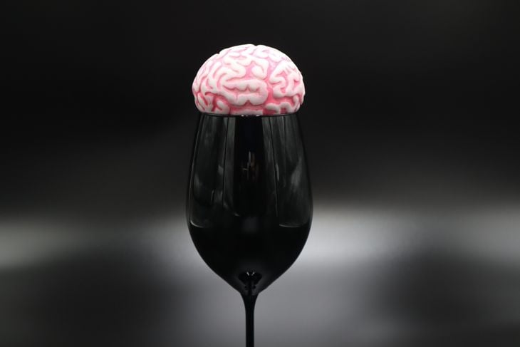 Black wineglass with human brain on top on black background