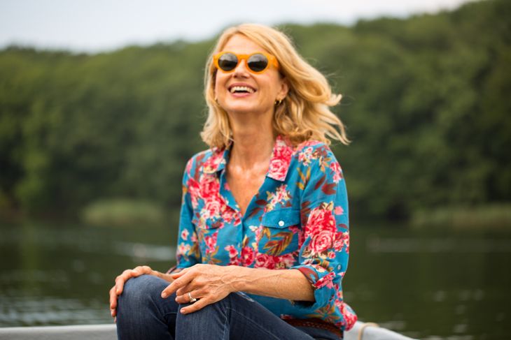 Mature woman sitting on rowboat in lake. Happy female is enjoying vacation in forest. She is wearing casuals while boating.