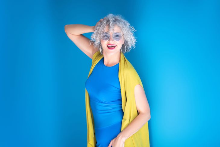 Happy and inspired. Confident mature woman wearing blue dress feeling truly happy and inspired