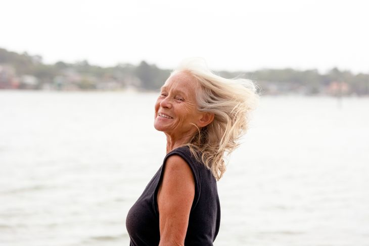 Portrait of smiling senior woman on windy day, outdoor, background with copy space, full frame horizontal composition