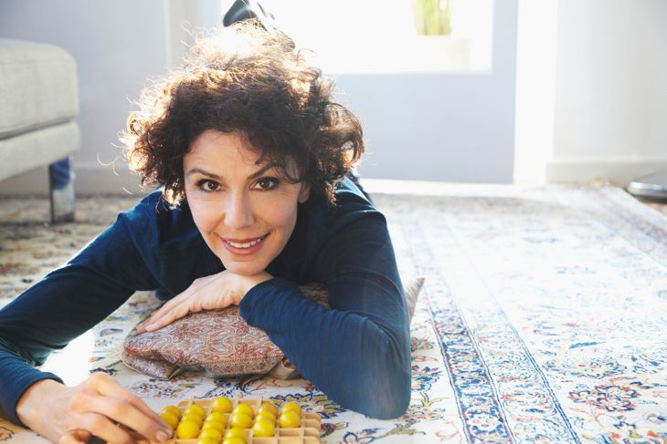 Portrait of relaxed woman lying on carpet with board game