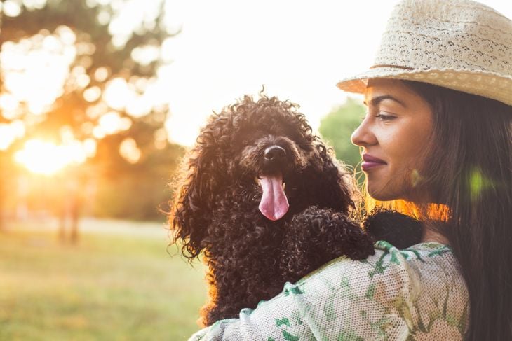 Woman holding her black poodle