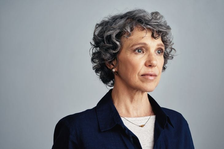 Studio shot of a mature woman looking uncertain against a gray background