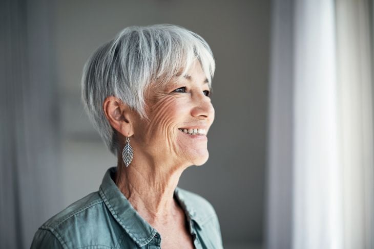 Shot of a happy elderly woman looking out the window at home