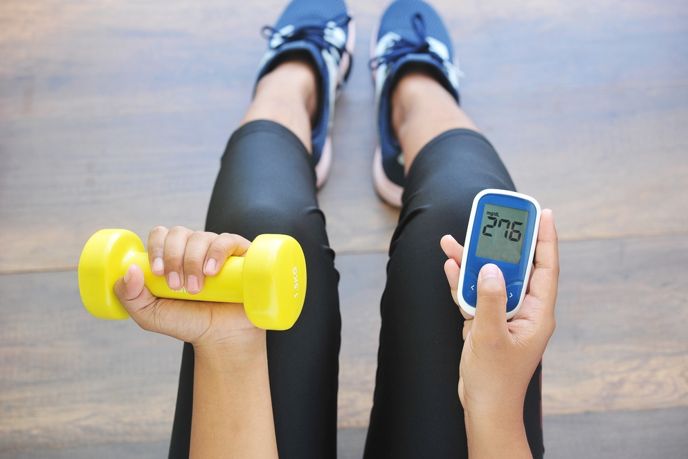 woman holding weight and blood sugar monitor