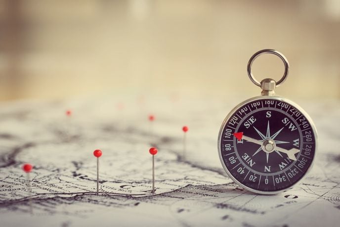 compass sitting on a map with pins