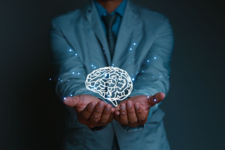 A person in a light suit holds out their hands with a glowing digital brain illustration hovering above, symbolizing the importance of accurate knowledge about Naegleria fowleri infection and how it enters the brain through the nose. 
