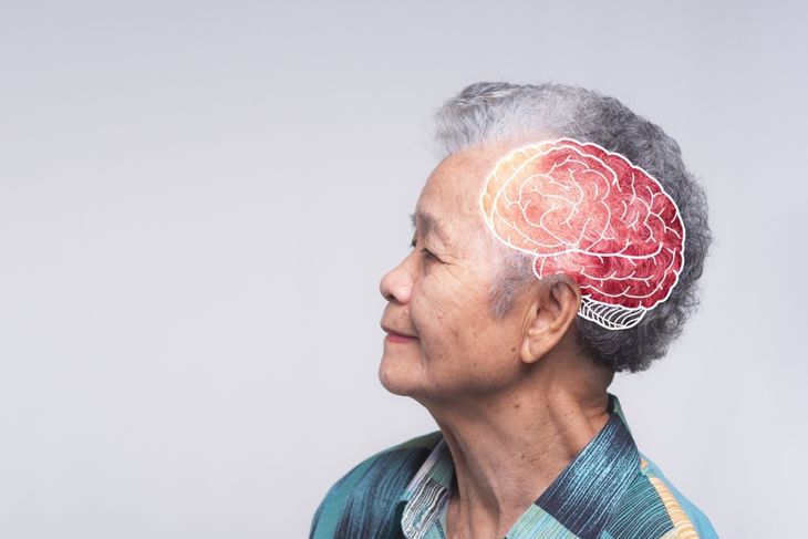 An older woman in profile smiles gently, with a digital illustration of a red and white brain overlaid on her head, highlighting the risk of neurological symptoms like seizures and loss of balance as brain involvement worsens. 