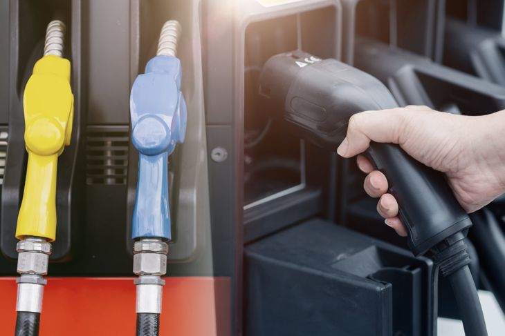 Duel energy vehicle alternative type compare EV charging station electricity car with old fuel nozzle at gas station