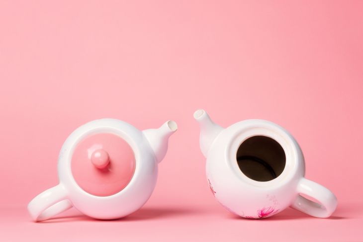 Breast Cancer Awareness Month. Two white porcelain teapots lying on a pink background. One teapot without a lid, symbolizing the disease.