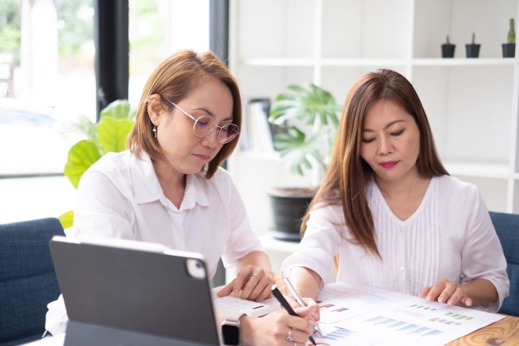 Concept of a mother and daughter co-signing a loan in a bank office