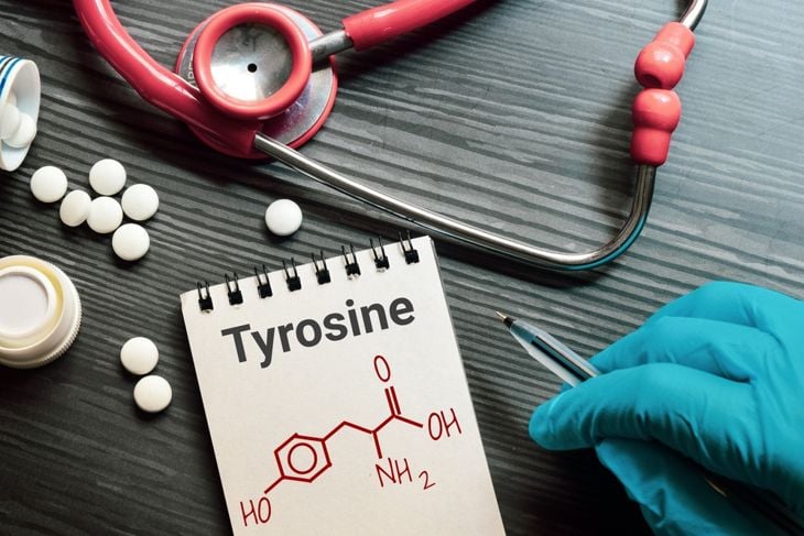 Notepad with the text and chemical structure of L Tyrosine on table with pills stethoscope.