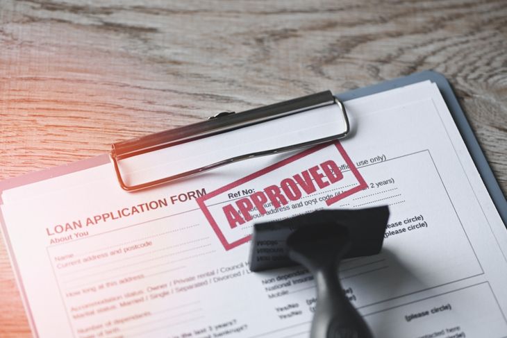 Loan approved on loan application form paper with rubber stamp on table