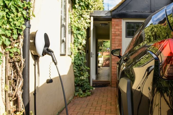 Electric car plugged in to charge outside home with power cable