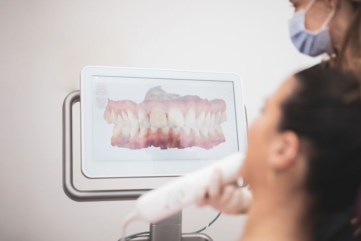 Woman dentist scanning patient's teeth with 3d dental scanner in modern clinic