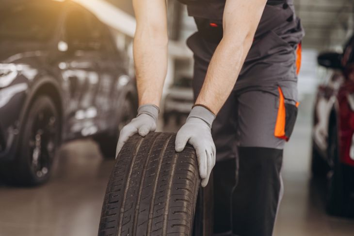 Car Mechanic holding a tire at the repair garage