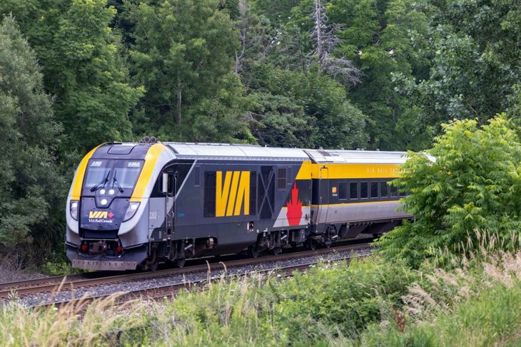 A sleek modern Via Rail Siemens locomotive pulling a Canadian passenger train toward Montreal from Toronto Union Station
