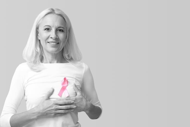 Mature woman with pink ribbon on light background with space for text. Breast cancer awareness concept