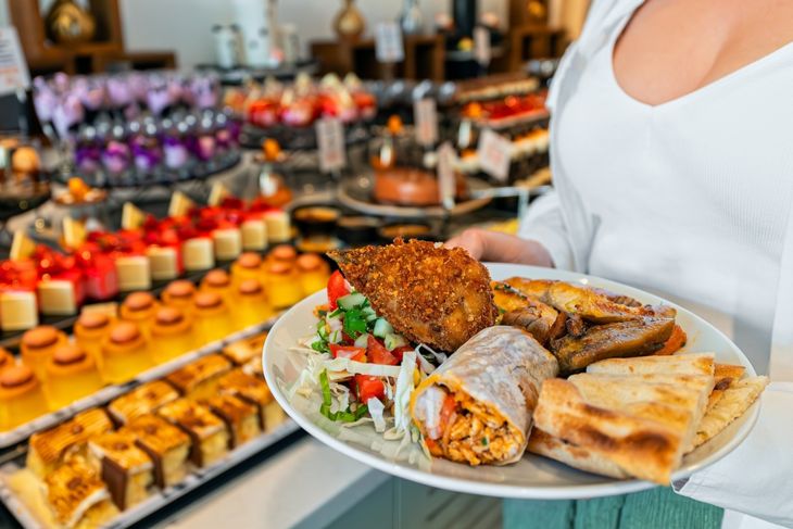 Woman holding a plate full of food. All inclusive concept