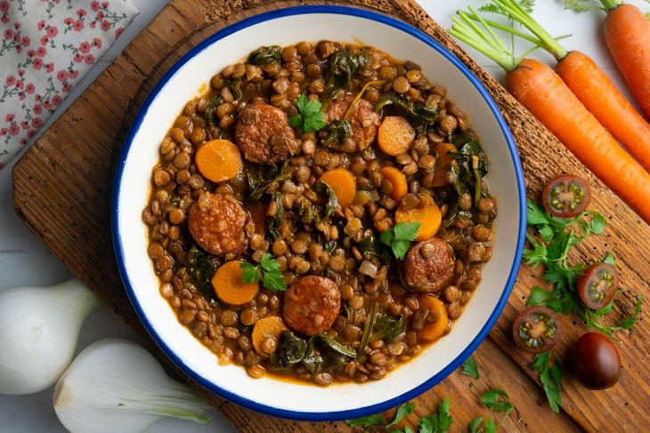 Lentil stew with chorizo, spinach and carrot. Top view table with decorations.