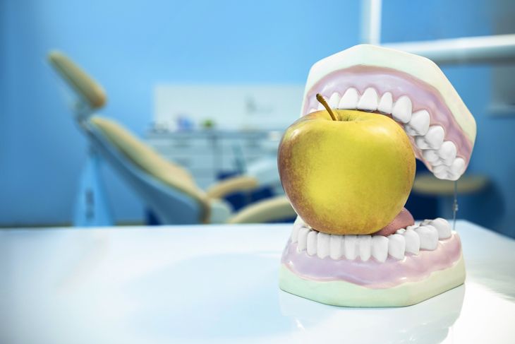 Dentures biting an apple in a dentist office